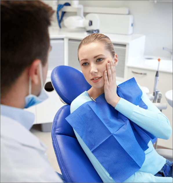 Woman holding cheek during emergency dentistry appointment