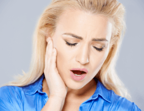 Woman hold jaw in need of TMJ therapy