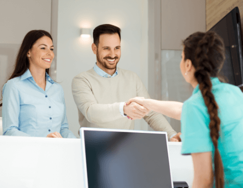 Man and woman checking in at dental office reception desk