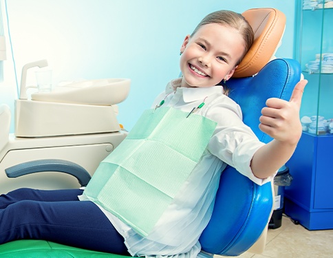 Young girl giving thumbs up after children's dentistry appointment