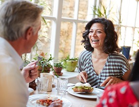 Woman smiling while eating with friends in restaurant