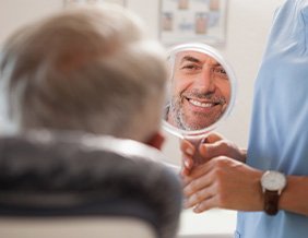 Man smiling at reflection in handheld mirror