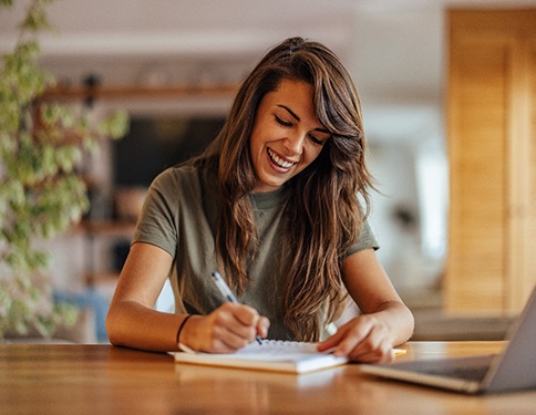 Woman smiling while writing something down on notepad