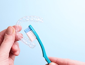 Patient holding clear aligner and toothbrush